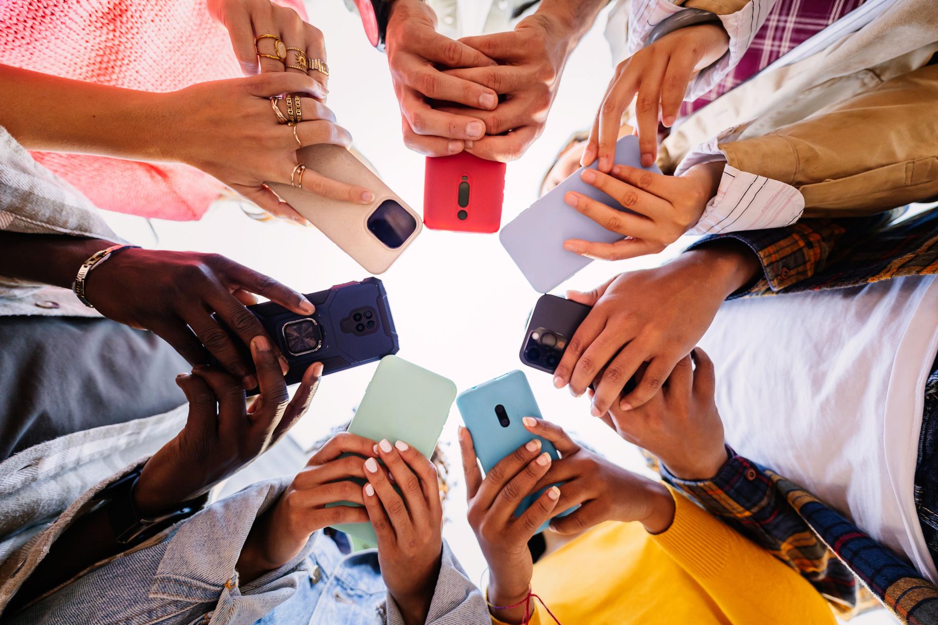 Young group of student people using smartphone together outside